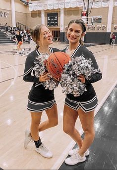 two girls in cheerleader outfits holding a basketball