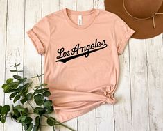 "Los Angeles Shirt, City Of Angels, Los Angeles Gifts, Los Angeles City, Los Angeles Tee, California La Shirt, Los Angeles California Shirt * Processing time is 1 business day (there may be exceptions during holiday seasons). Delivery time is based on your shipping type selection and location. Please check the estimated delivery times at checkout and upgrade the shipping at checkout if you need it sooner. * All items are made-to-order. Because of the nature of these items, unless they arrive dam City Los Angeles, La Shirt, Los Angeles Shirt, California Shirt, Los Angeles City, City Of Angels, Iron Decor, Los Angeles California, Festival Season