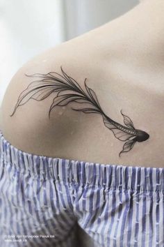 the back of a woman's shoulder with a feather tattoo on her left side