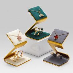 four jewelry boxes are stacked on top of each other with rings and pendants in them