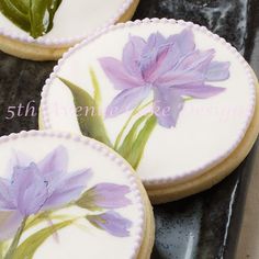 three decorated cookies with purple flowers on them