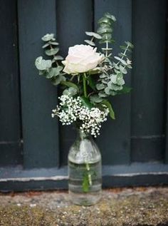 a vase filled with white flowers sitting on top of a floor next to a window