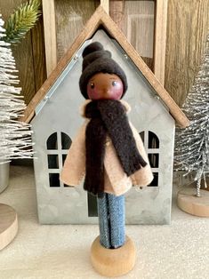 a doll is standing in front of a house with a scarf around it's neck