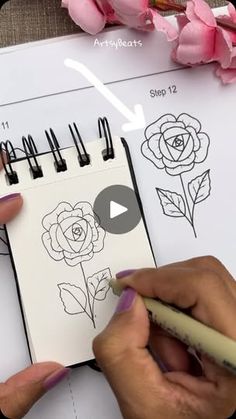 a person is drawing flowers on a sheet of paper with markers and pencils in front of them