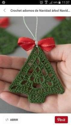 a hand holding a crochet ornament with a red bow on it