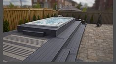 a large hot tub sitting on top of a wooden deck next to a fenced in yard