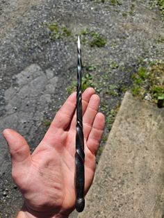 a hand holding a small metal object in it's left hand on the ground