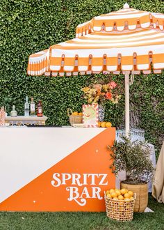 an orange and white striped umbrella next to a small bar with lemons on it