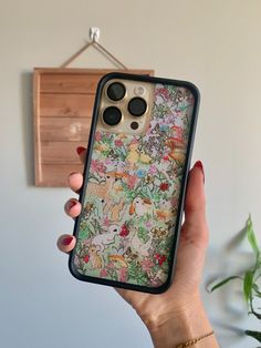 a woman holding up her phone case with an image of animals on the front and back