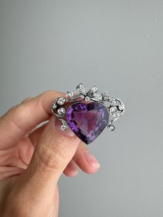 A romantic symbol of love from the turn of the 20th century, France. A regal and deeply saturated amethyst heart, bracketed by diamond lined scrolls and crowned with a glittering rose-cut diamond bow, is a visual reminder that love is a precious gift. This would have been gifted to someone who was seen as their "Queen", carrying the sentiment, "ruler of my heart". Hand fabricated in 18k gold and platinum. French eagle's head hallmark and maker's mark for Herve Menard. Measurements: 35 mm east to Ruler Of My Heart, Georgian Jewelry, Amethyst Heart, Diamond Bows, Diamond Crown, Bow Brooch, Precious Gift, Diamond Brooch, Heart Brooch