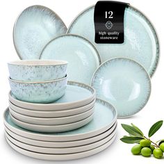 a stack of blue and white dishes next to some green olives on a white background