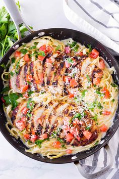 chicken and tomato pasta in a skillet with parmesan cheese on the side