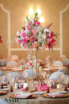 a tall vase filled with pink and white flowers sitting on top of a dining room table