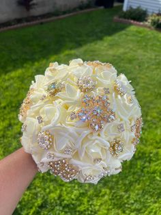 the bridal bouquet is being held by someone's hand in front of some green grass