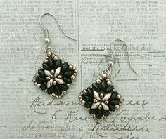 black and white flower earrings on top of a piece of paper with writing in the background