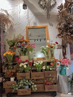 a room filled with lots of different types of flowers and plants on top of wooden crates