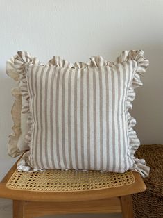 a striped pillow sitting on top of a wooden chair next to a wicker basket