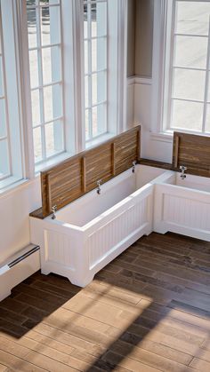 a white bath tub sitting next to two windows in a room with wooden floors and walls