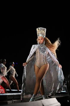 a woman in a bodysuit and crown walks down the runway