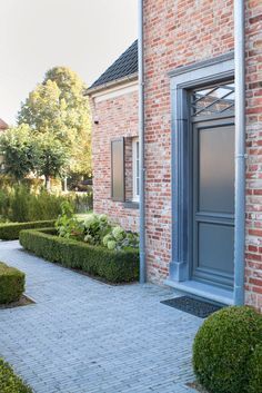 a brick house with hedges and bushes around it