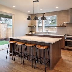 a kitchen with three stools next to an island in the middle of the room