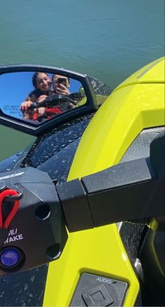 the reflection of two people in a rear view mirror on a yellow motorbike