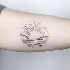 a woman's arm with a sun and clouds tattoo on the left inner arm