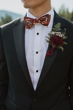 a man in a tuxedo with a red flower on his lapel and bow tie