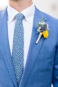 a man wearing a blue suit and tie with a boutonniere on his lapel