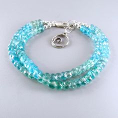 "Two strands of gorgeous aqua blue and sea green faceted apatite gemstones are strung on strong nylon coated flexible stainless steel beading wire. The bracelet has a very 'beachy' feel to it. These are gorgeous 6mm. stones with lots of color. They are shaded from aqua blue to a beautiful green. The clasp is a sturdy lobster claw and the other end is a portion of large linked chain, that allows you to hook the clasp into any link for a custom fit. I have added a circular wave charm to continue w Adjustable Blue Apatite Bracelets, Adjustable Apatite Beaded Bracelets, Faceted Apatite Turquoise Jewelry, Beading Wire, Sea Green, Adjustable Bracelet, Aqua Blue, Lobster Claw, Arm Band