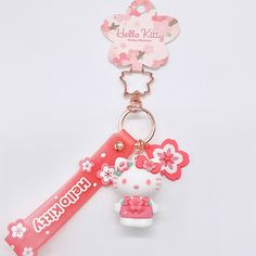 a hello kitty keychain is shown on a white background with pink flowers and a name tag