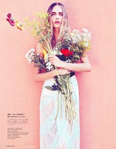 a woman holding flowers in front of a pink wall