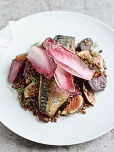 a white plate topped with vegetables and lentils on top of a stone countertop