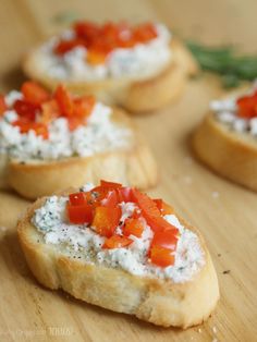 small pieces of bread with cheese and tomatoes on them sitting on a wooden table top