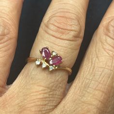 a woman's hand with a ring on it that has an oval shaped ruby and white diamond set in the middle