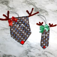 two ties with reindeer heads on them are sitting on a marble counter top, one has a green bow and the other is red