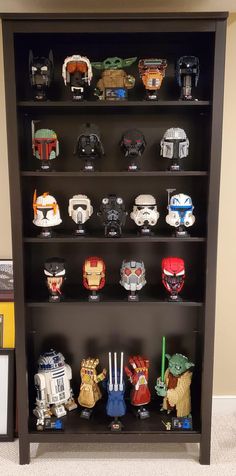 a book shelf filled with star wars masks and figurines on top of it