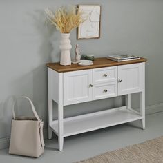 a white cabinet with two drawers and a basket on the floor in front of it