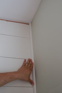 a person's hand is on the edge of a white paneled wall with horizontal stripes