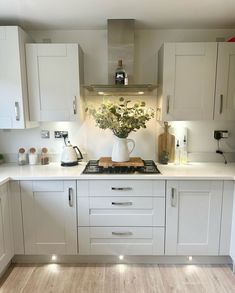 a kitchen with white cupboards and an island in the middle is lit by lights