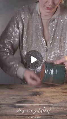 a woman pouring something into a cup on top of a wooden table