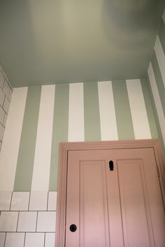 a bathroom with green and white stripes painted on the wall above the door to the toilet