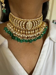 Be your own kind of beautiful. Simply a mark of royalty and elegance! You will definitely fall in love with the beautifully placed green stones with Kundan Stone embellishments. One of our favourite picks for the wedding season ❤️ The pearl drops add perfect glamour to the gorgeous piece. The pretty statement earrings add to the royalty of the stunning choker necklace. Weight of Earrings: 18 grams per pair. Length of the earrings: 6 cm Width of the earrings: 2.5 cm Traditional Green Jeweled Jewelry, Green Jeweled Kundan Necklace, Green Chandbali Jewelry For Celebration, Green Stone Work Jewelry For Gifts, Elegant Green Chandbali Kundan Necklace, Green Jewelry With Stone Work For Gift, Green Kundan Gemstone Jewelry Set, Green Kundan Gemstone Necklace For Party, Kundan Jewelry Set With Green Gemstones