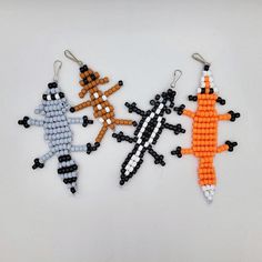 three beaded toy animals are sitting on a white surface, one is orange and the other is black