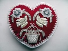 a red heart with white flowers and birds on it