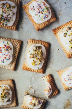 small desserts with white frosting and sprinkles arranged on a baking sheet