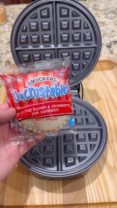 someone is holding up a bag of waffles on a cutting board next to a sandwich maker