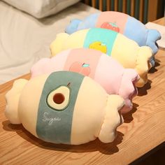 three stuffed animals sitting on top of a wooden table next to a pillow and blanket