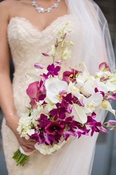 a bride holding a bouquet of purple and white flowers