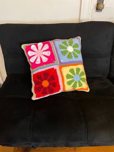 a black couch with a crocheted pillow on it